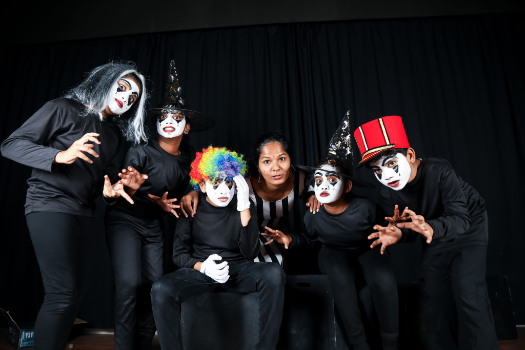 A group of mime artists pose in colorful costumes during a theatrical performance.