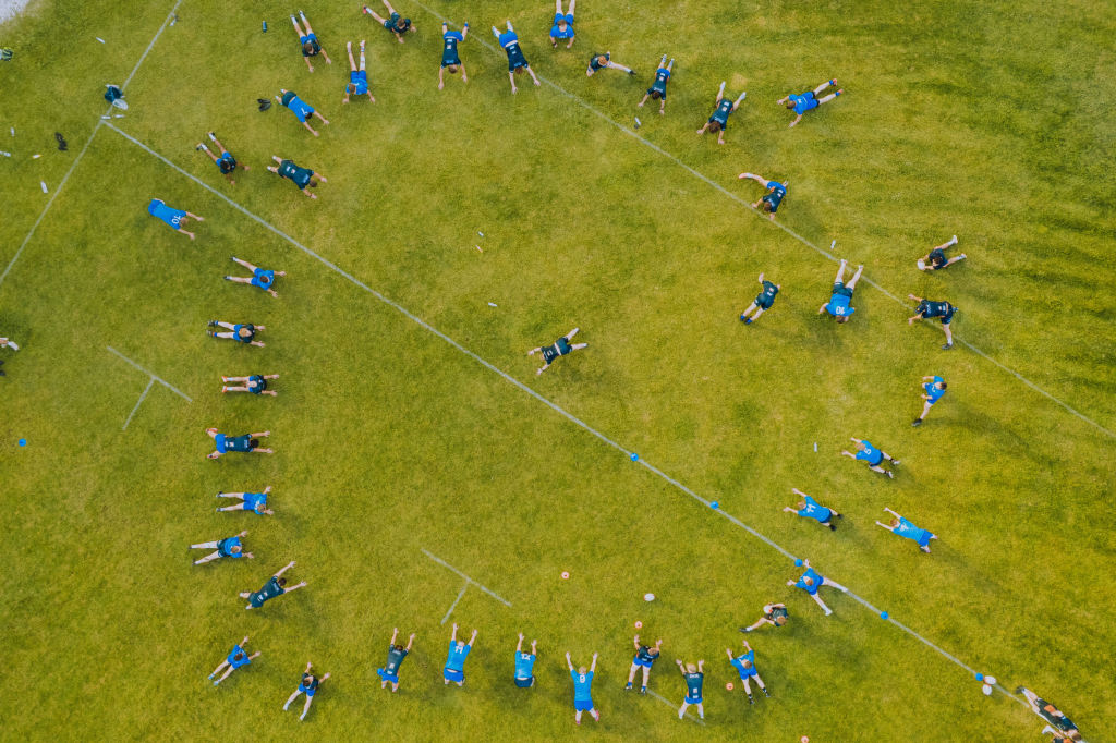 Aerial photo of a sports team practicing on a grassy field in a circular formation.