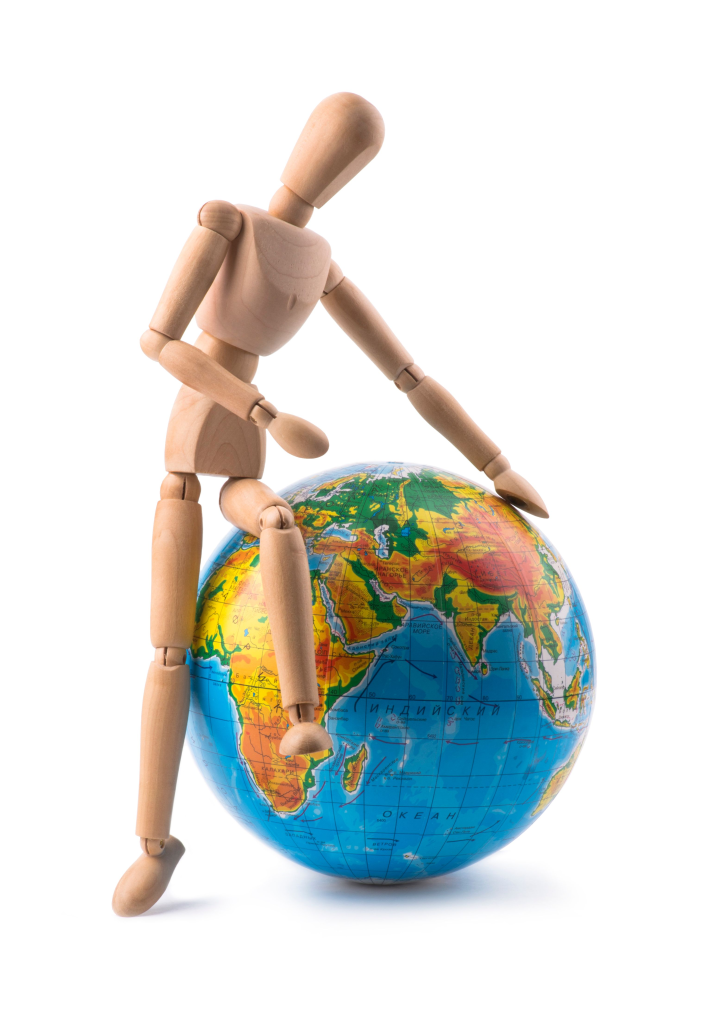 A wooden mannequin sits creatively on a colorful globe, symbolizing global unity.