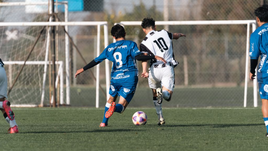 Dynamic moment in a soccer match with players competing for the ball on a clear day.