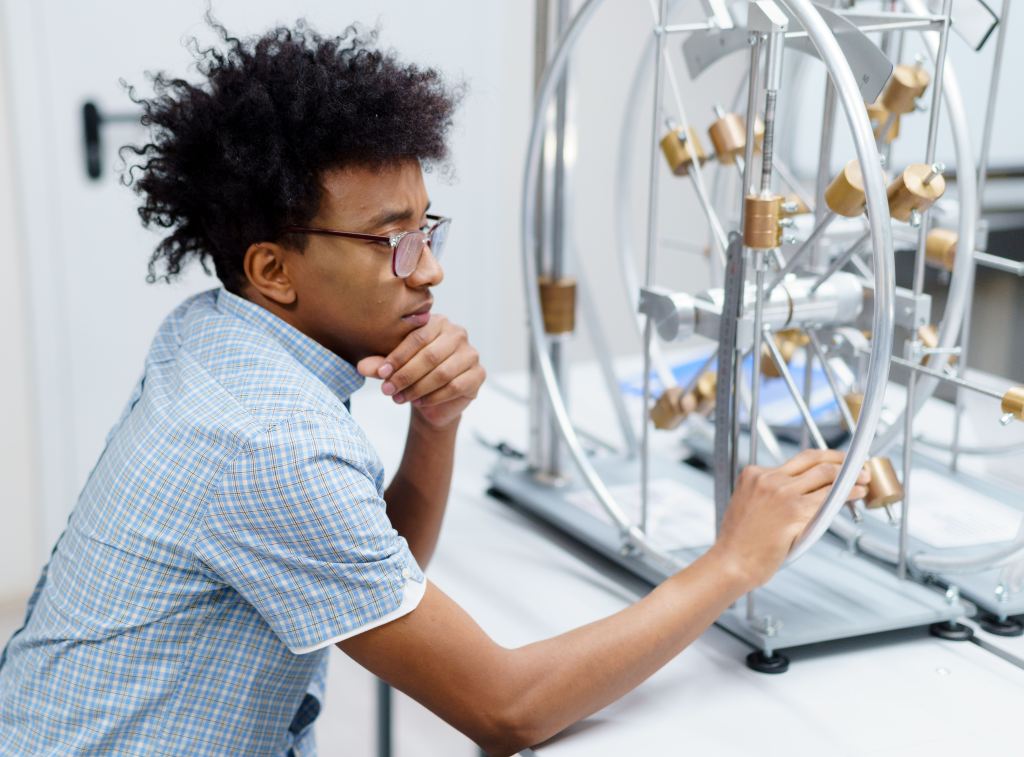 Student analyzing scientific equipment in a lab setting, engaged in learning.