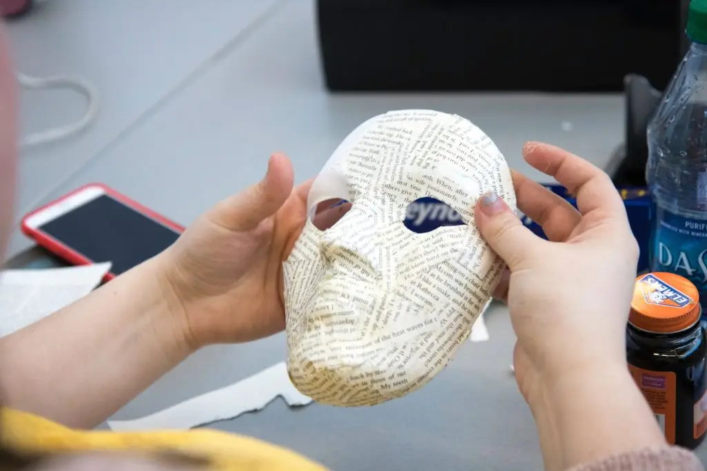 Close-up of crafting a paper mache mask during an art class project.