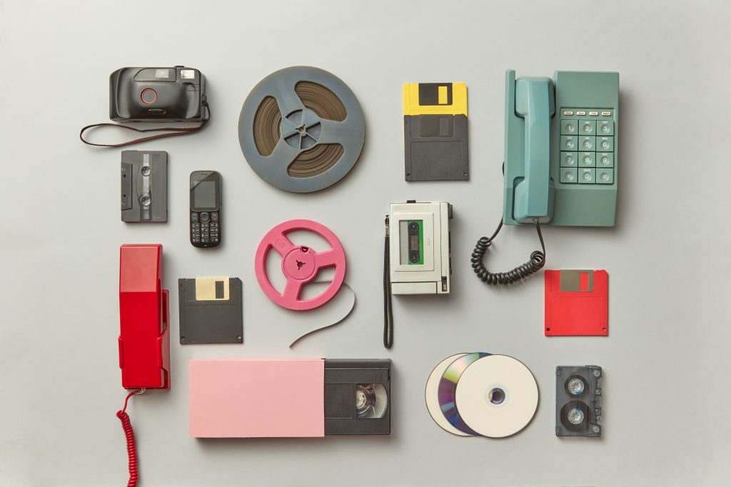 Collection of vintage gadgets including telephones, cassettes, and floppy disks.