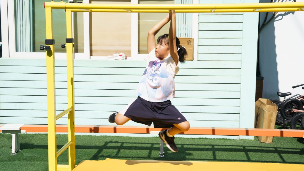 A young girl enjoys a sunny day on an outdoor jungle gym, showing off her playful spirit.